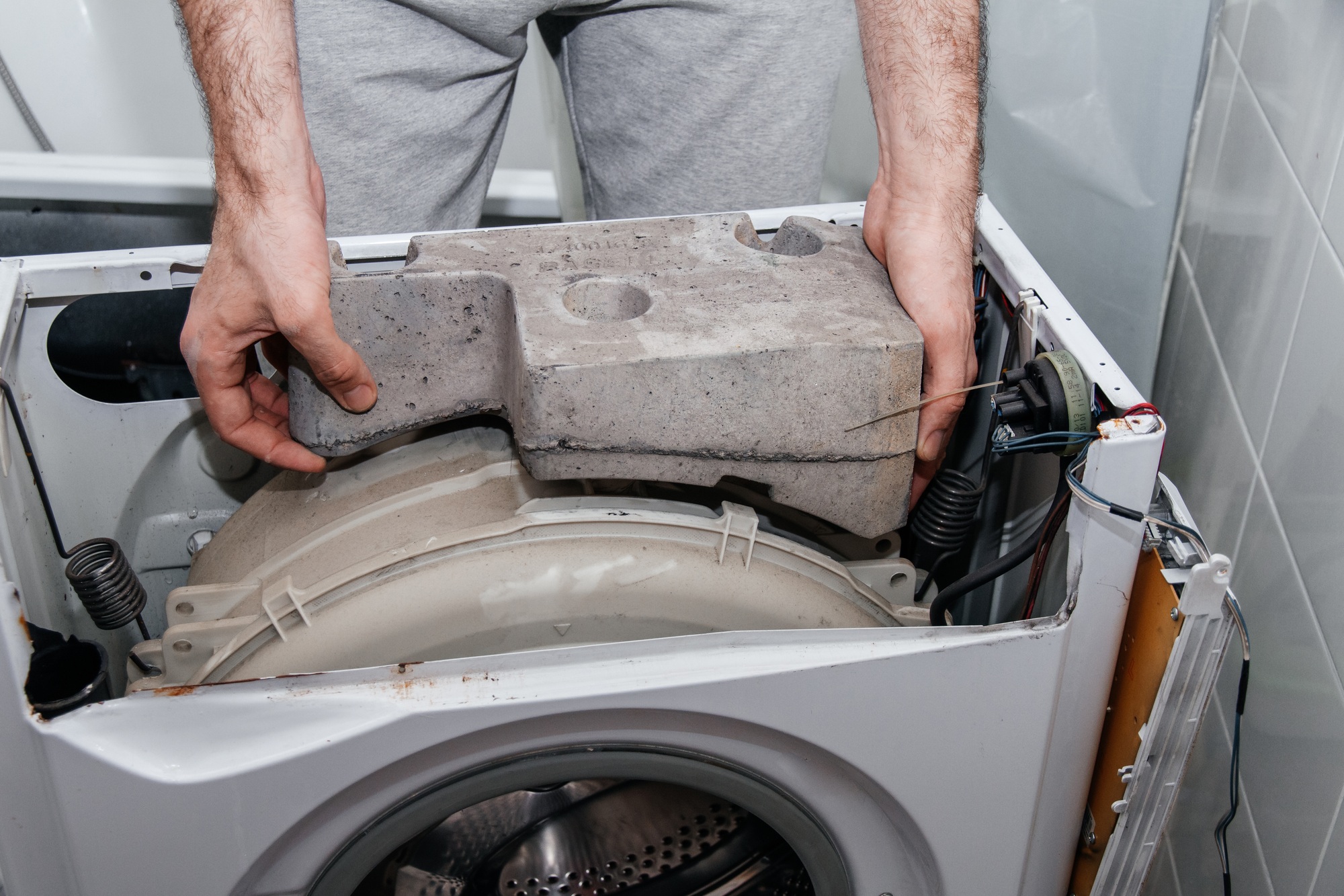 Handyman repairing a washing machine. The hands of a man repair a washing machine.
